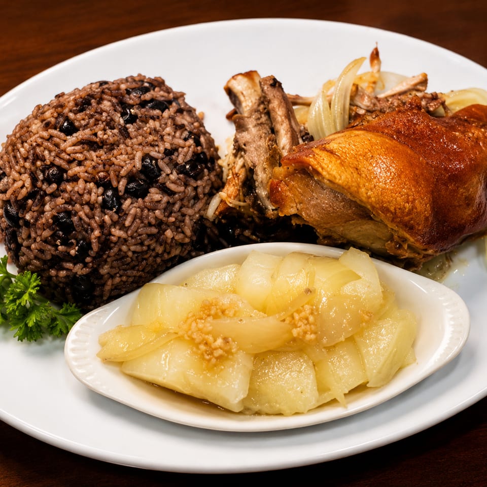 Plate of roasted meat, black bean rice, sautéed onions, and parsley garnish on a white dish.